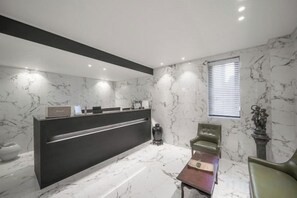 A modern reception area with a marble wall, a reception desk, and a seating area. - hotel onggi (Gyeongju)