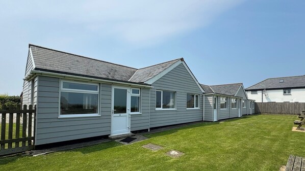 A row of single-story, grey mobile homes with white trim and large windows.