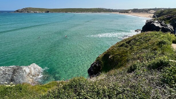 A coastal landscape with clear turquoise waters, rocky cliffs, and a distant beach. - Atlantic View Chalets #2 | Self-catering holiday cottage near Crantock beach (Crantock)