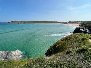 A coastal landscape with clear turquoise waters, rocky cliffs, and a distant beach.