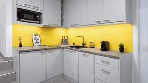 Eine moderne Küche mit weißen Schränken, einer gelben Spritzschutzkleidung, einer Bosch-Mikrowelle, einem Spülbecken und einer Kaffeemaschine.