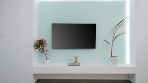 Ein modernes Zimmer mit einem wandmontierten Flachbildfernseher, einem kleinen Tisch mit Topfpflanze und einer Bank.