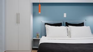 Ein Schlafzimmer mit einem Bett, einem Nachttisch, einem kleinen Tisch mit einer Vase und einem Kleiderschrank.