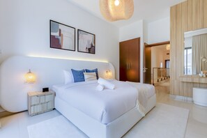 A modern bedroom with a large bed, bedside tables, a mirror, and artwork on the wall.