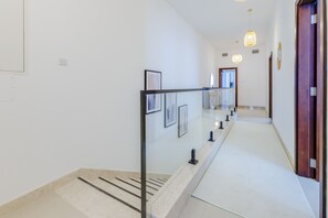 A modern interior with a glass railing, a staircase, and framed artwork on the walls.