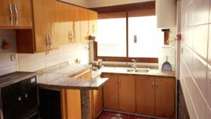 Una cocina con armarios de madera, encimera de granito, un lavabo y una ventana.