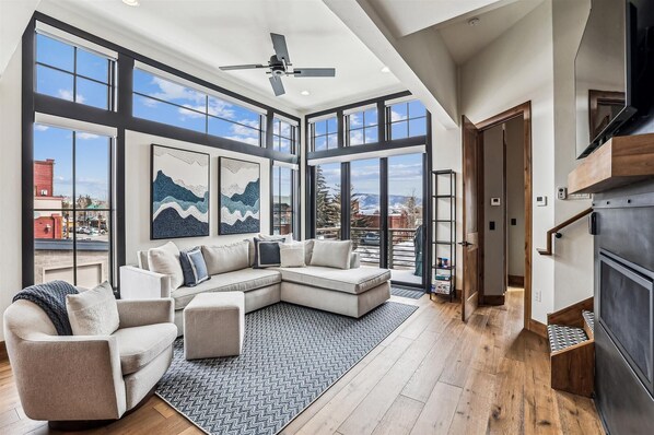 Relax in this stylish living room with a large sofa, coffee table, and fireplace, offering a view of the city.