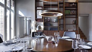 A dining area with a round table set for a meal, surrounded by bookshelves filled with books and decorative items. - Luxurious 300 sqm Apartment with Canal View in Cannaregio (Venezia)