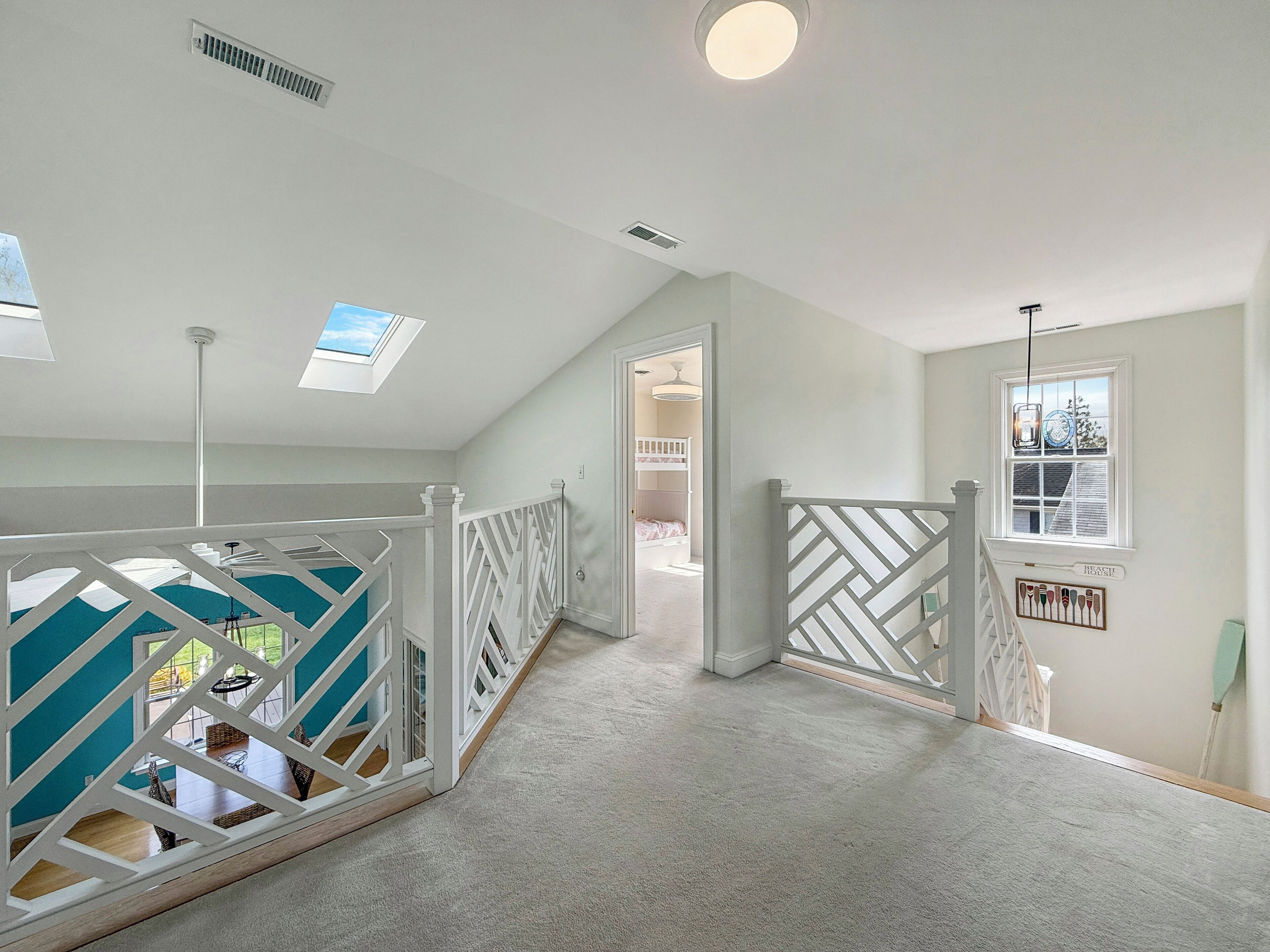 A spacious room with a high ceiling, a skylight, and a view of a balcony.