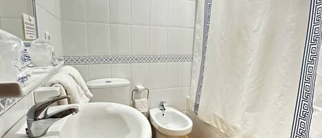 A bathroom with a sink, bidet, and toilet.
