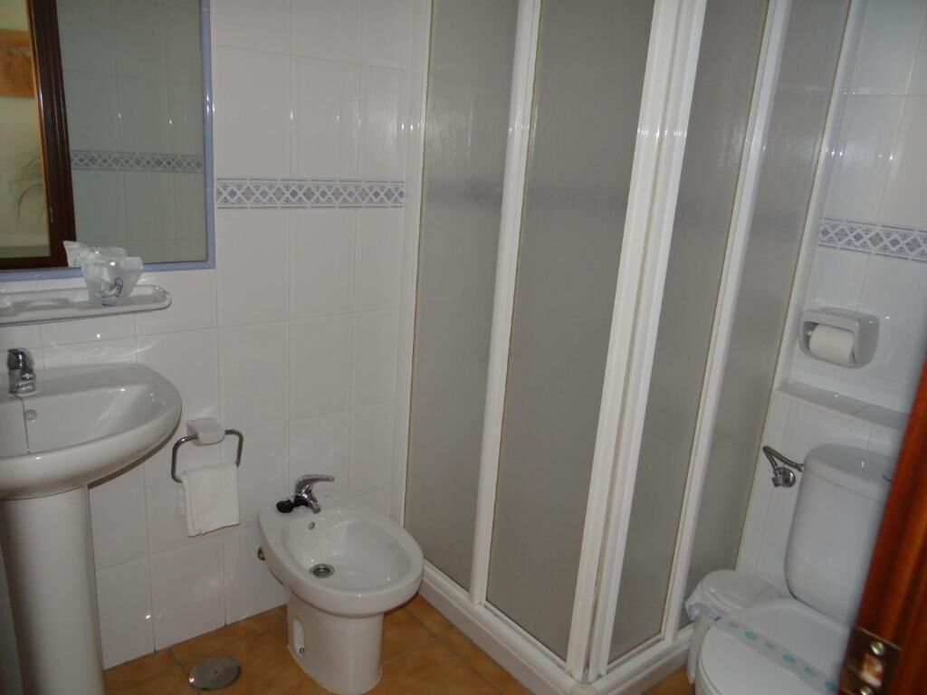 Un baño con lavamanos, bidé, inodoro y cabina de ducha.