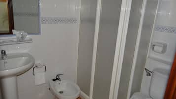 Un baño con lavamanos, bidé, inodoro y cabina de ducha.