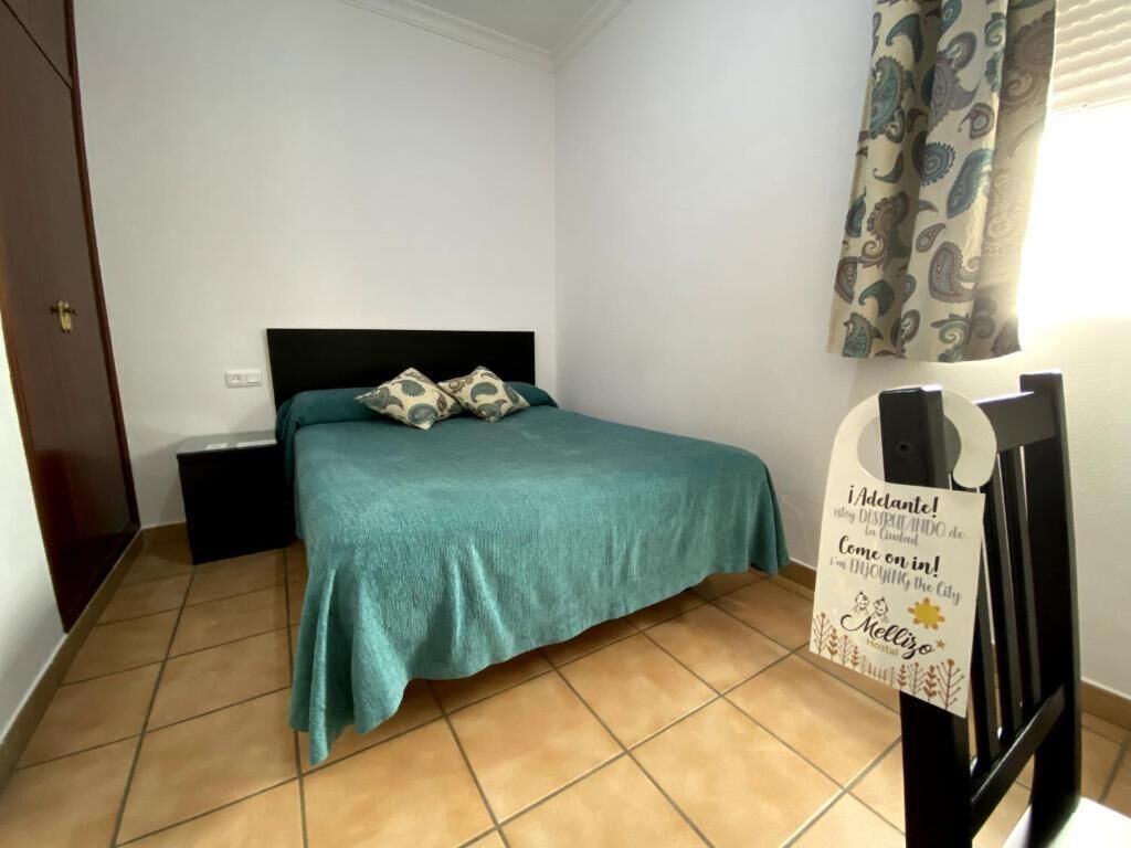 A bedroom with a bed, a nightstand, and a wall-mounted sign.