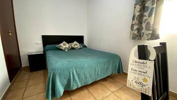 A bedroom with a bed, a nightstand, and a wall-mounted sign.
