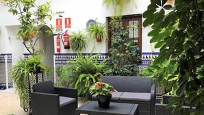 Cortile con mobili in vimini, piante in vaso e cartello della reception.