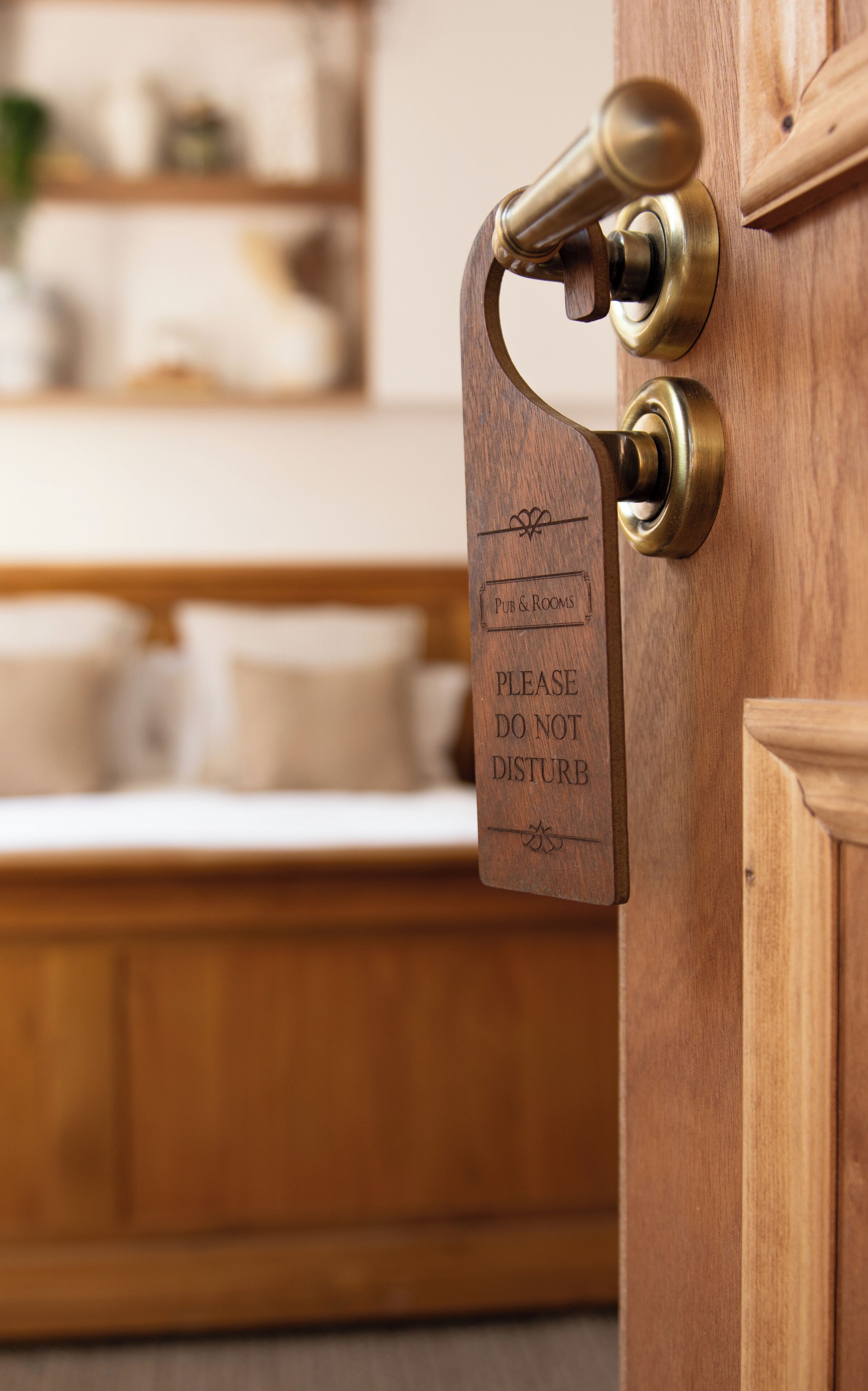 A wooden door with a brass doorbell and a sign that reads "PUB & ROOMS PLEASE DO NOT DISTURB."