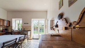 A kitchen with a dining area, wooden furniture, and a view through a glass door.