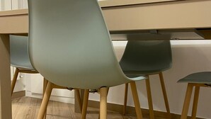 Une pièce avec un plancher en bois, un bureau et deux chaises aux pieds en bois.