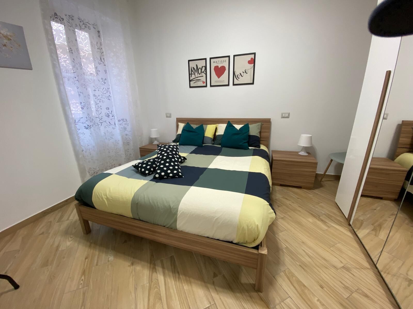 Ein ordentlich eingerichtetes Schlafzimmer mit einem Bett, Nachttischen und einem Spiegel.