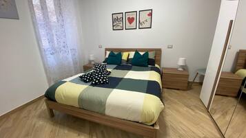 Ein ordentlich eingerichtetes Schlafzimmer mit einem Bett, Nachttischen und einem Spiegel.