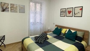 Une chambre à coucher comprenant un lit, une chaise, une table de chevet et des œuvres d’art murales.
