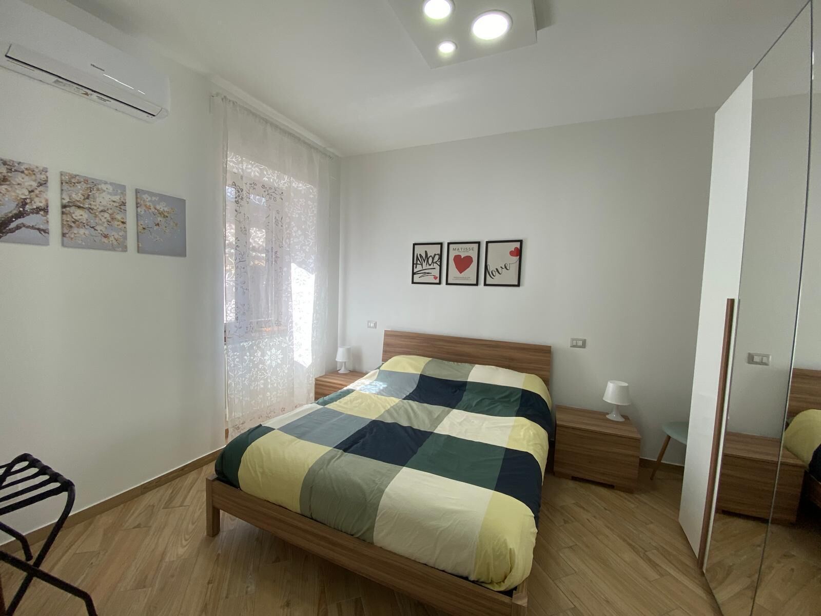Ein Schlafzimmer mit einem hölzernen Bett, Nachttischen und einem großen Spiegel.