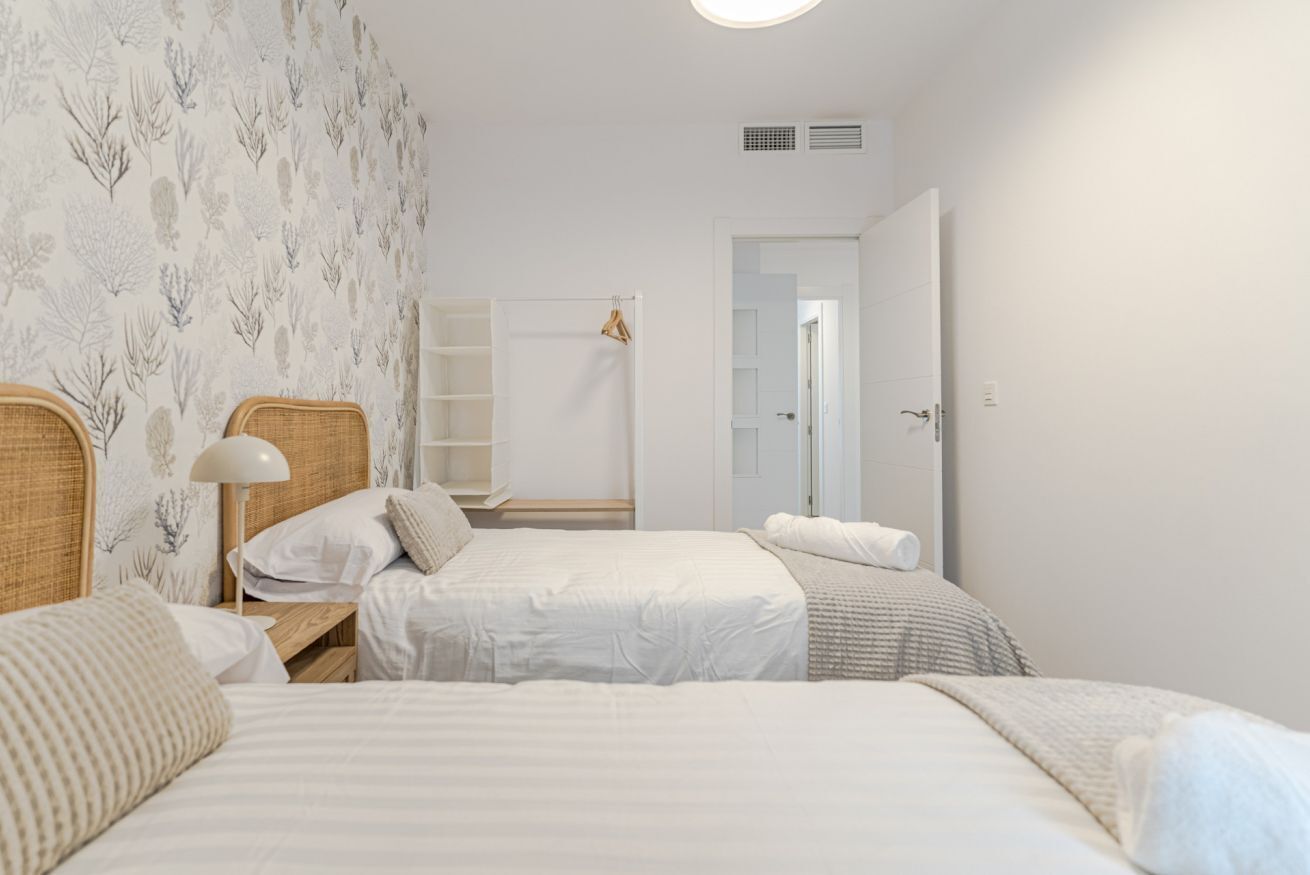 Ein Schlafzimmer mit zwei Betten, einem Nachttisch mit Lampe und einem Kleiderschrank.
