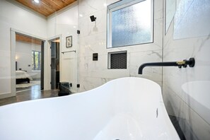 Une salle de bain moderne avec une baignoire sur pieds, un grand miroir et un espace douche.