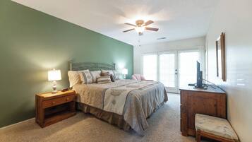 A bedroom with a bed, nightstand, chair, and a ceiling fan.