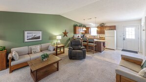 A living room with a sofa, armchair, coffee table, and a kitchen area in the background. - One Bedroom Marina View Condo (Grand Rivers)