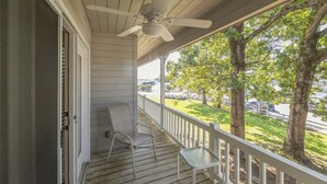 A covered porch with a ceiling fan, two chairs, and a small table. - One Bedroom Marina View Condo (Grand Rivers)