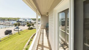 A balcony with a view of a marina, a covered car, and a grassy area. - One Bedroom Harbor View Condo (Grand Rivers)