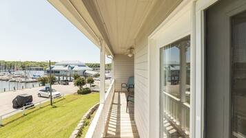 A balcony with a view of a marina, a covered car, and a grassy area.