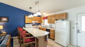 A compact kitchen with wooden cabinets, a white refrigerator, a microwave, and a sink. - One Bedroom Harbor View Condo (Grand Rivers)