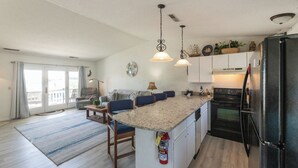 A modern kitchen with a central island, pendant lighting, and a refrigerator. - One Bedroom Harbor View Condo (Grand Rivers)