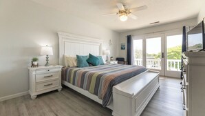 A bedroom with a bed, nightstands, a dresser, a ceiling fan, and a view of the outdoors through a sliding glass door. - One Bedroom Harbor View Condo (Grand Rivers)
