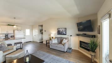 Ein Wohnzimmer mit einer Couch, einem Couchtisch und einem an der Wand montierten Fernseher.