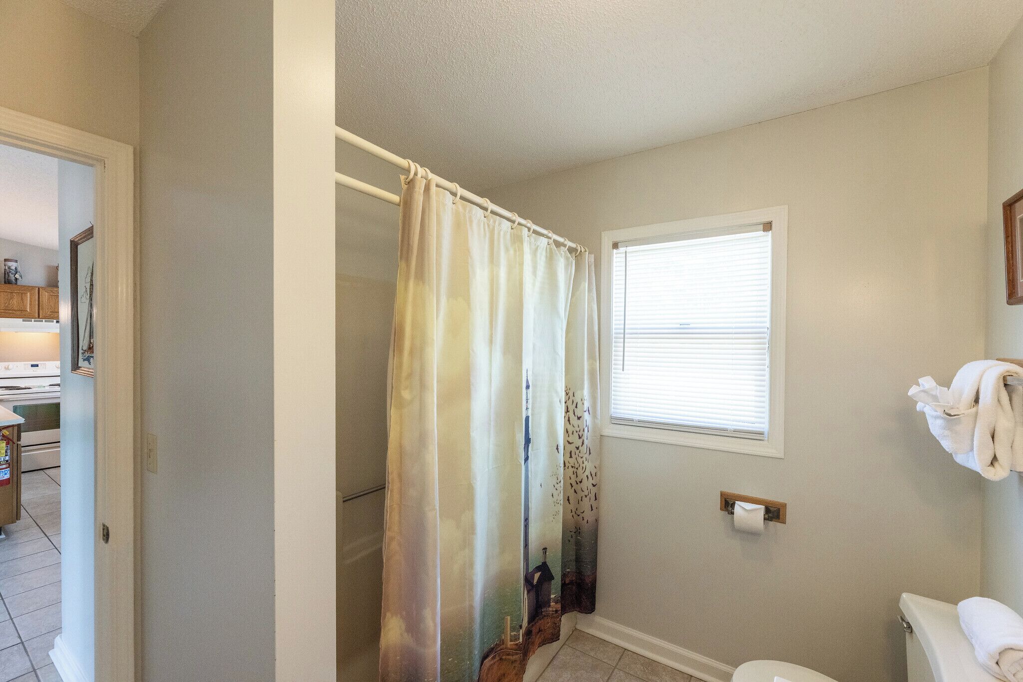 Une salle de bain avec un rideau de douche, des toilettes et une fenêtre.