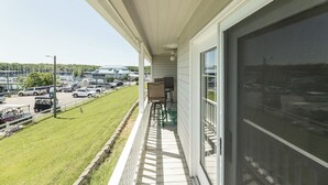 Un balcon donnant sur un parking et une zone verdoyante.