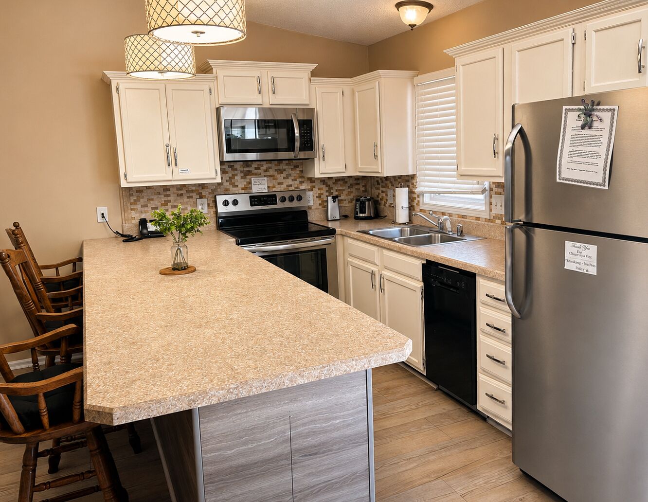 A kitchen with white cabinets, stainless steel appliances, a granite countertop, and a wooden dining set.
