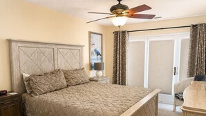 Une chambre à coucher avec un lit, une table de chevet, une lampe et un ventilateur de plafond.