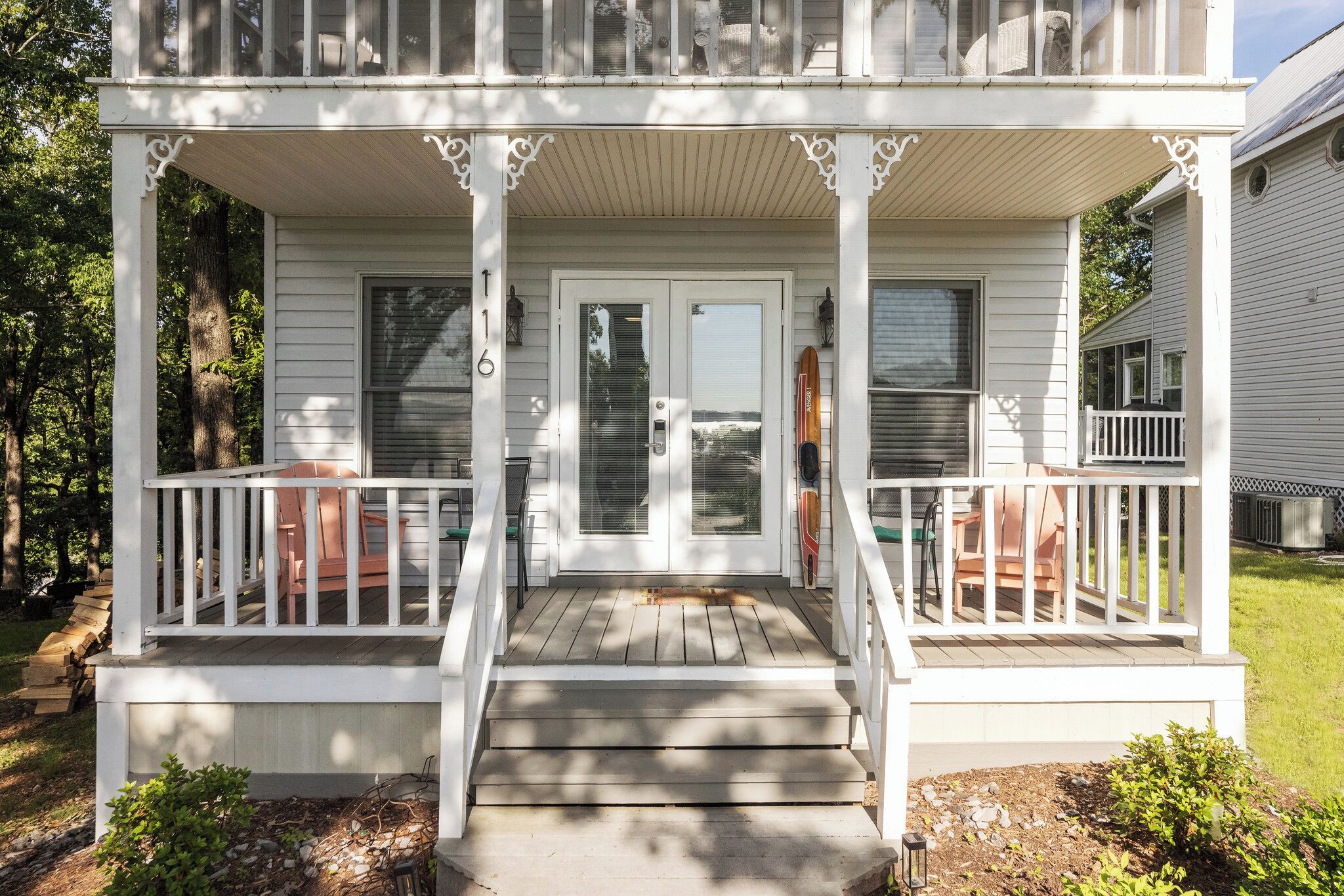 A two-story white house with a covered porch, a front door, and a small front yard.