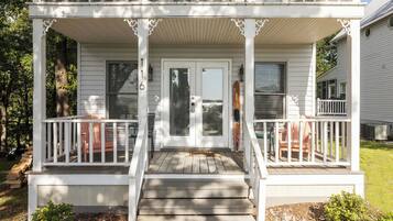 A two-story white house with a covered porch, a front door, and a small front yard.