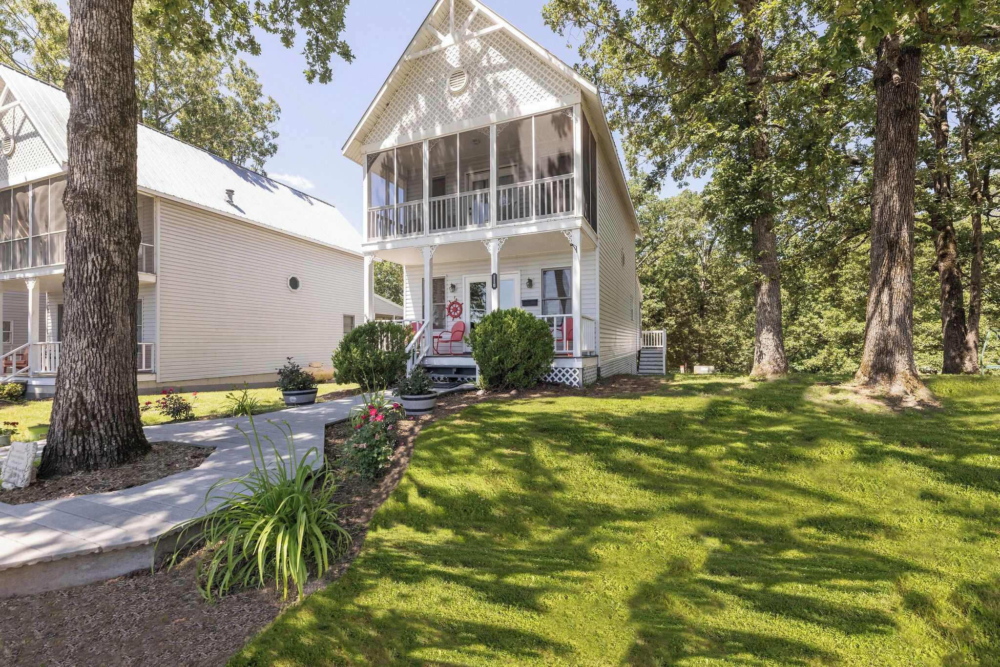 A two-story house with a balcony, surrounded by trees and a well-maintained lawn.