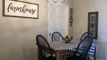 Un coin repas avec une table et des chaises, un lustre et une enseigne indiquant « ferme ».