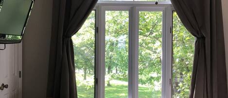 A room with a bed, a chair, a television, and a window with curtains.