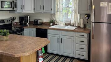 A kitchen with white cabinets, a stainless steel refrigerator, a microwave, a toaster, and a sink.