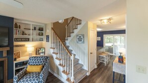 A living room with a staircase, a fireplace, a sofa, and a dining area.