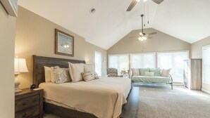 A bedroom with a large bed, a bench, a chair, and a ceiling fan. - Two Bedroom Harbor View Condo (Grand Rivers)