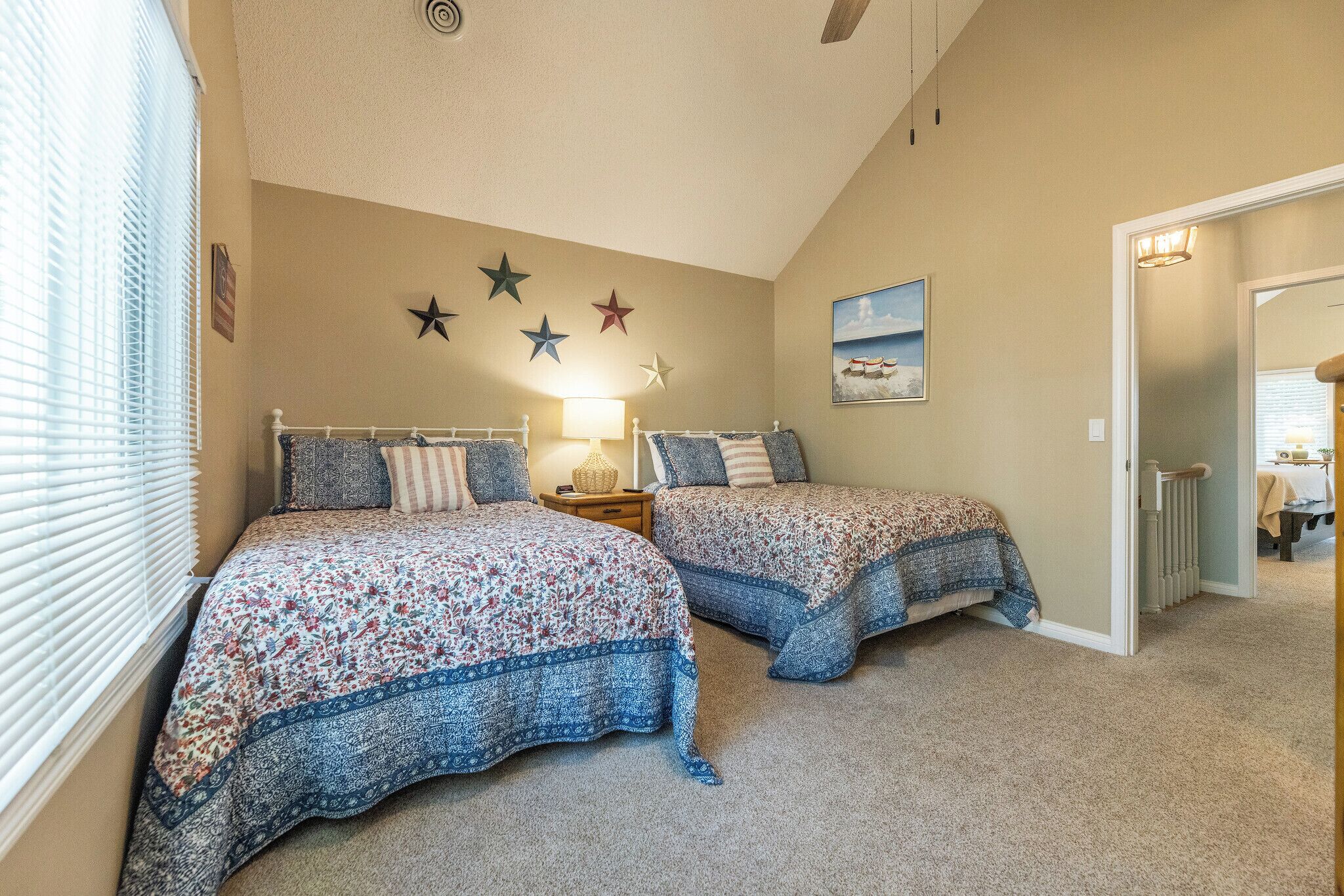 A bedroom with two beds, a nightstand, a lamp, and a star decoration on the wall.